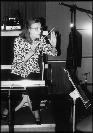 A middle-aged lady with a conductor's baton